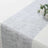 Silver textured table runner on a white table with floral accents.