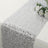 Silver sequin table runner with a floral arrangement on a plain surface