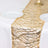 Gold beaded table runner on a white tablecloth with plates and glassware.