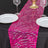 Pink sequin table runner on a black table setting with plates and glasses.