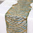 Gold and green decorative table runner on a white tablecloth.