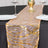 Gold sequined table runner on a black table with plates and glasses.