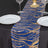 Blue and gold sequin table runner on a black table with plates and glasses.