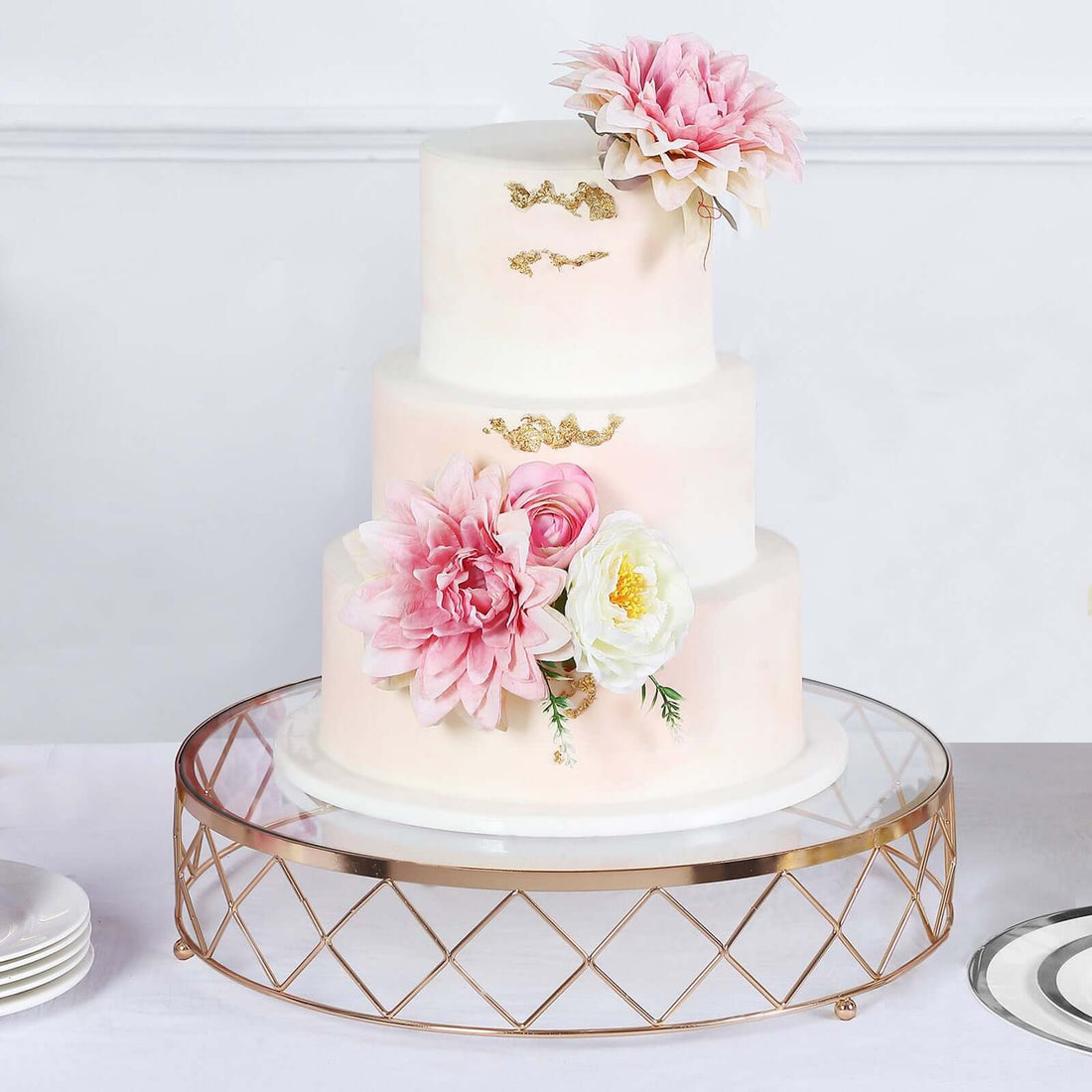 Elegant three-tier wedding cake adorned with pink and white flowers.