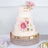 Elegant three-tier wedding cake adorned with pink flowers and gold accents.