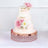 Elegant three-tier wedding cake adorned with pink flowers and gold accents.