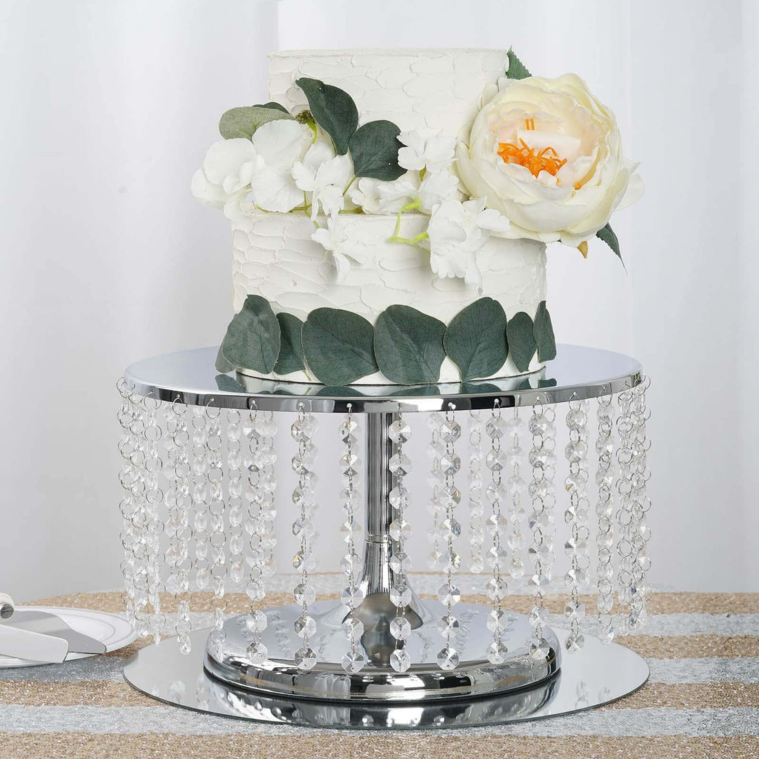 Elegant wedding cake on a crystal pedestal with floral accents.