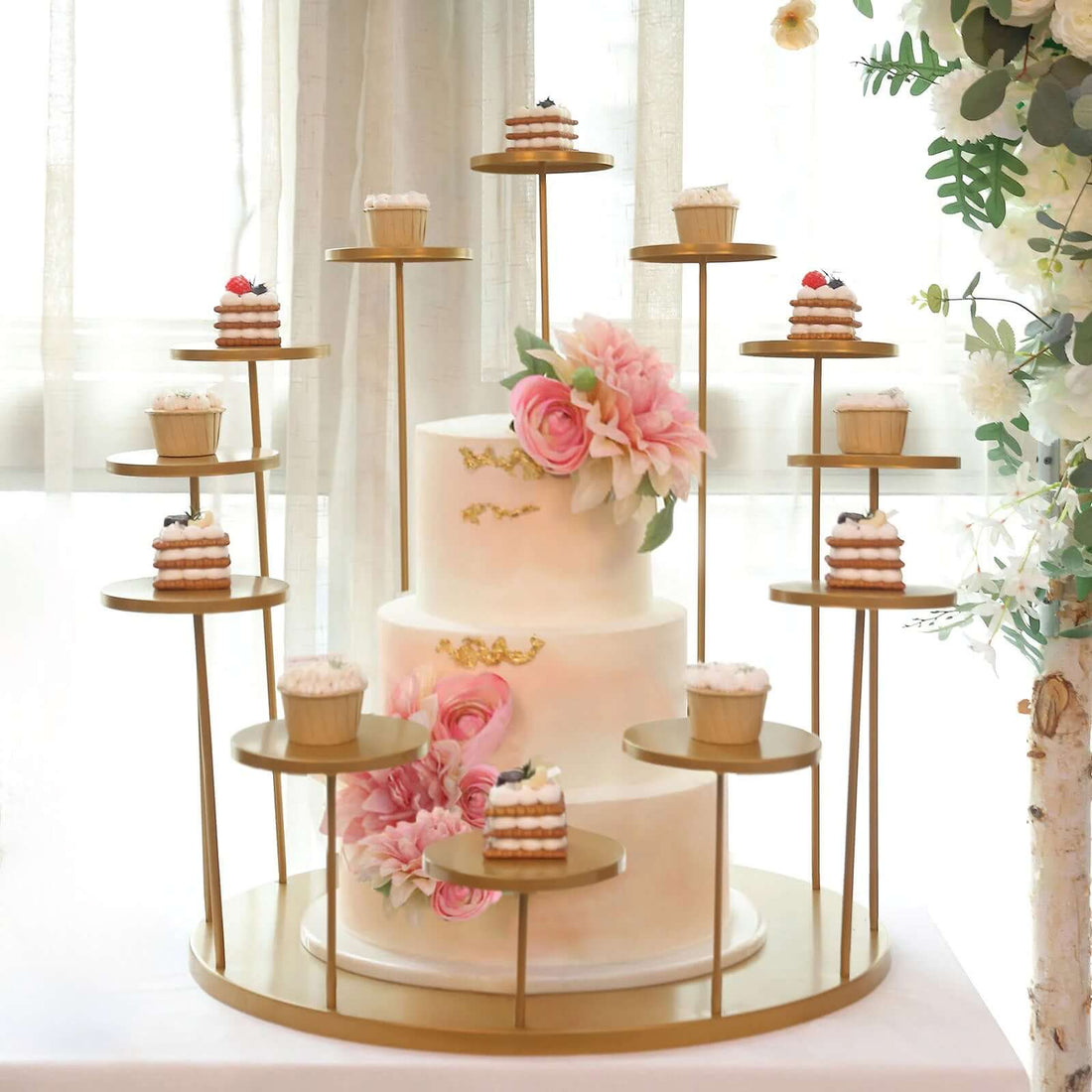 Elegant wedding cake with mini desserts on a decorative stand.