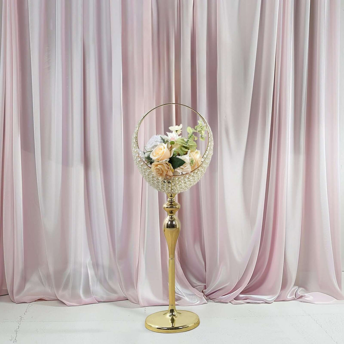 Elegant gold flower stand with a round vase holding soft pastel roses and white blooms.
