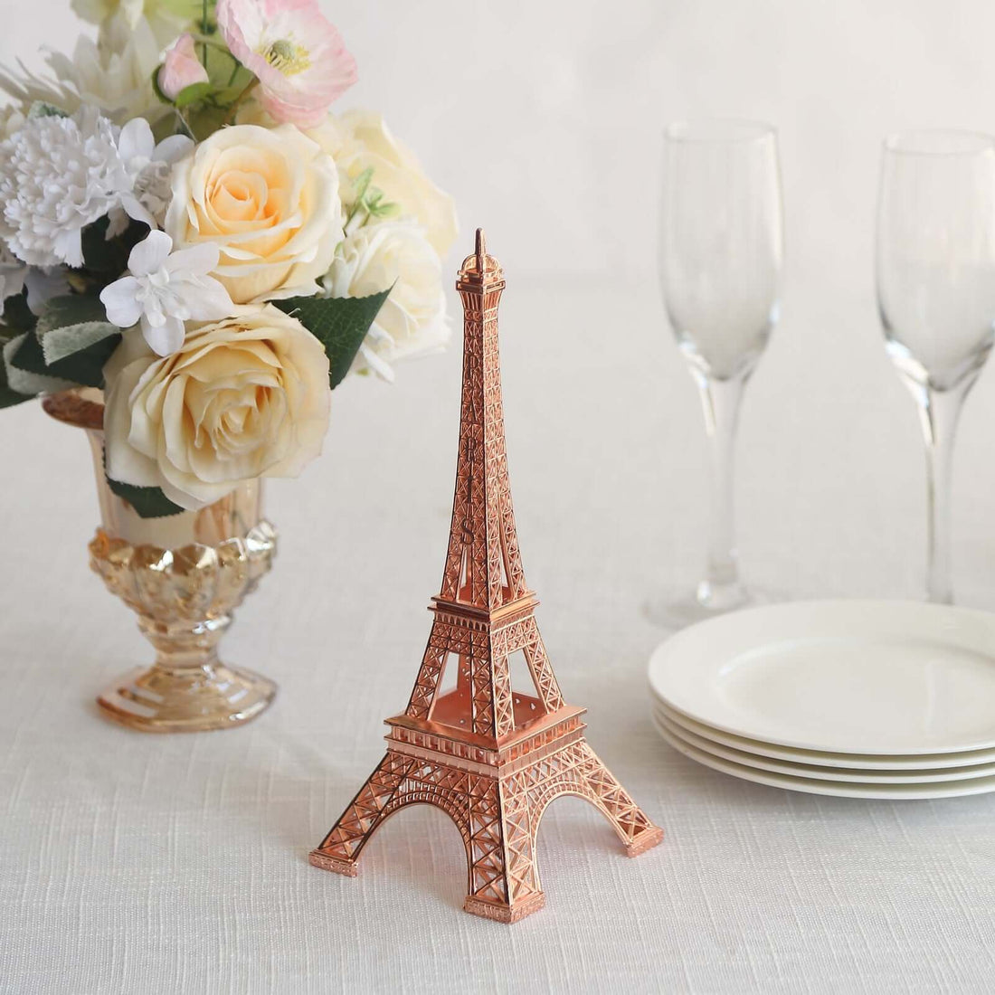 Eiffel Tower replica next to flowers and tableware in a styled setting.