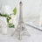 Silver Eiffel Tower figurine on a marble surface with flowers and candle.