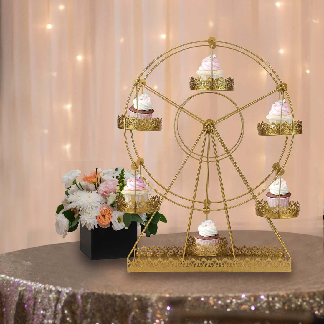 Gold cupcake ferris wheel display with cupcakes and flowers in a festive setting.