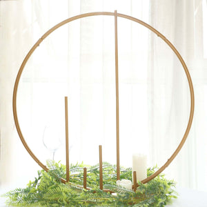 Gold circular candle holder with greenery and candles, studio shot.