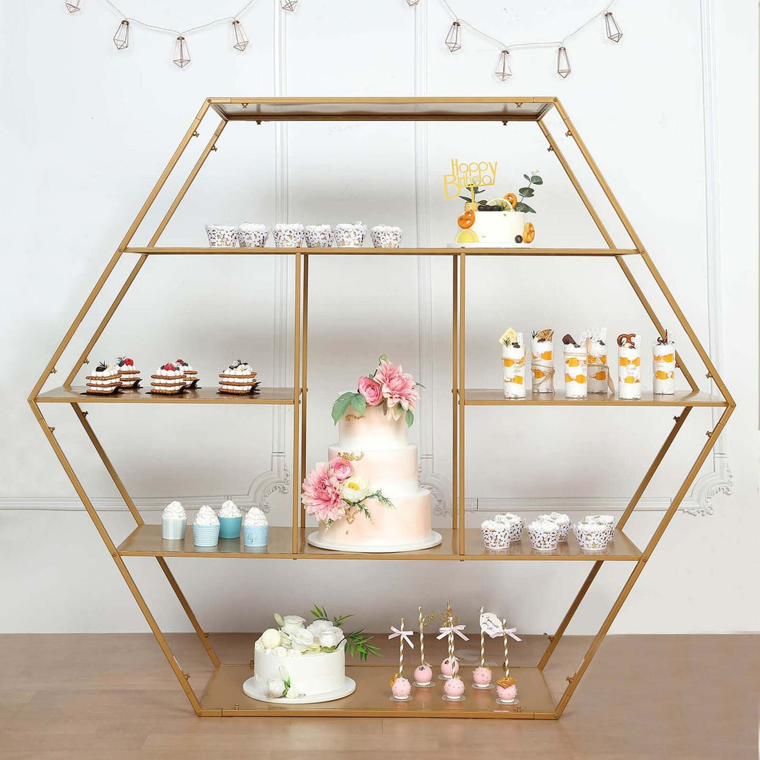 Decorative dessert display with a cake and assorted treats on a geometric shelf.