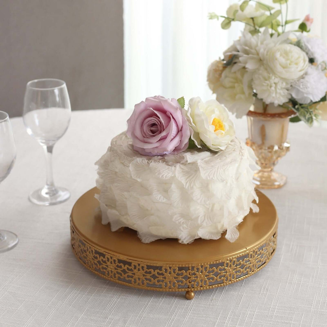 Elegant floral cake on a gold stand with decorative flowers.
