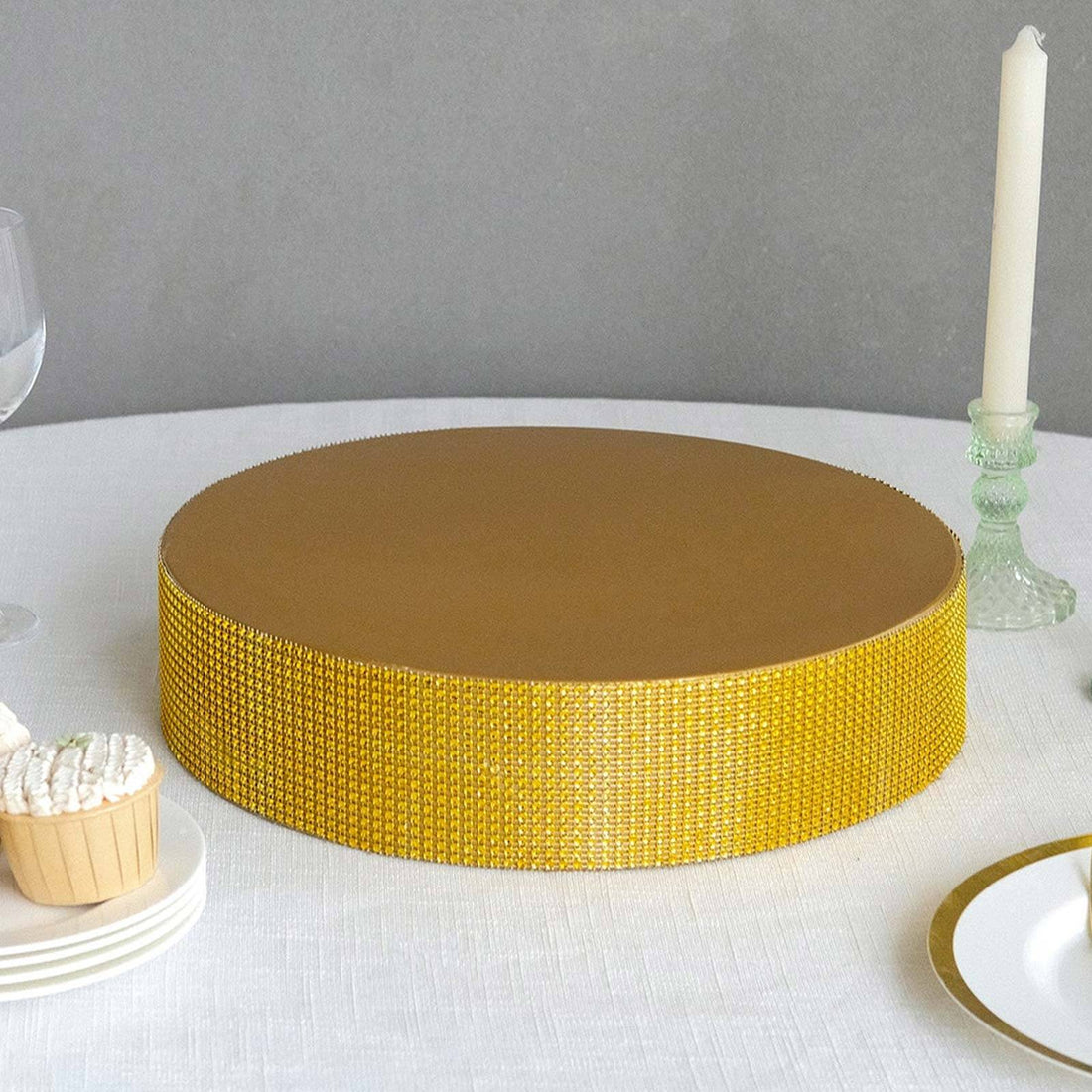 Gold cake stand with textured base on a table setting.