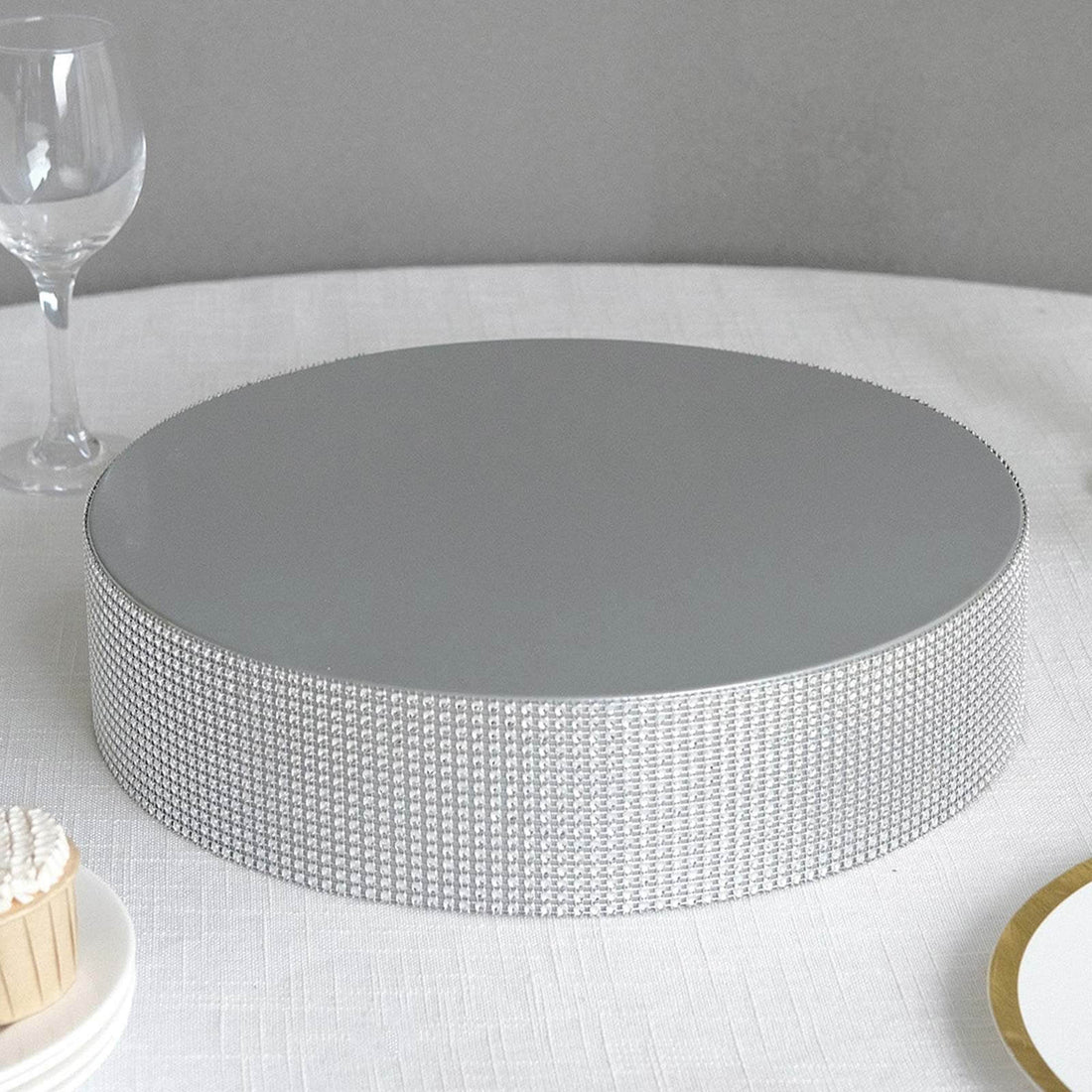 Silver cake stand with a mirrored top and textured base.