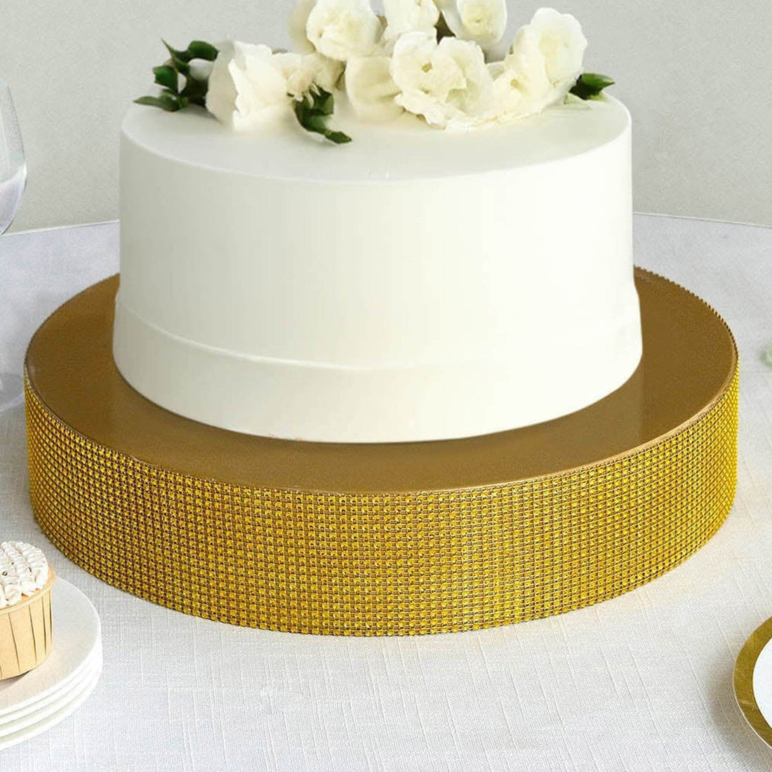 White cake with floral decoration on a gold cake stand.