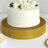 White cake with floral decoration on a gold cake stand.