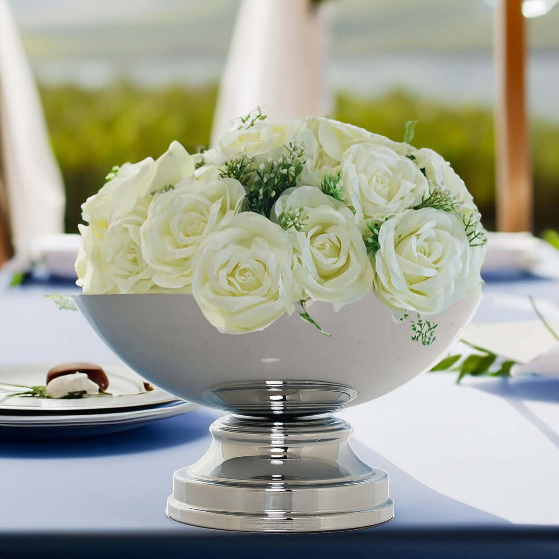 Elegant white rose centerpiece in a silver bowl on a table setting.
