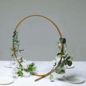 Decorative floral arch centerpiece with greenery and flowers on a table.