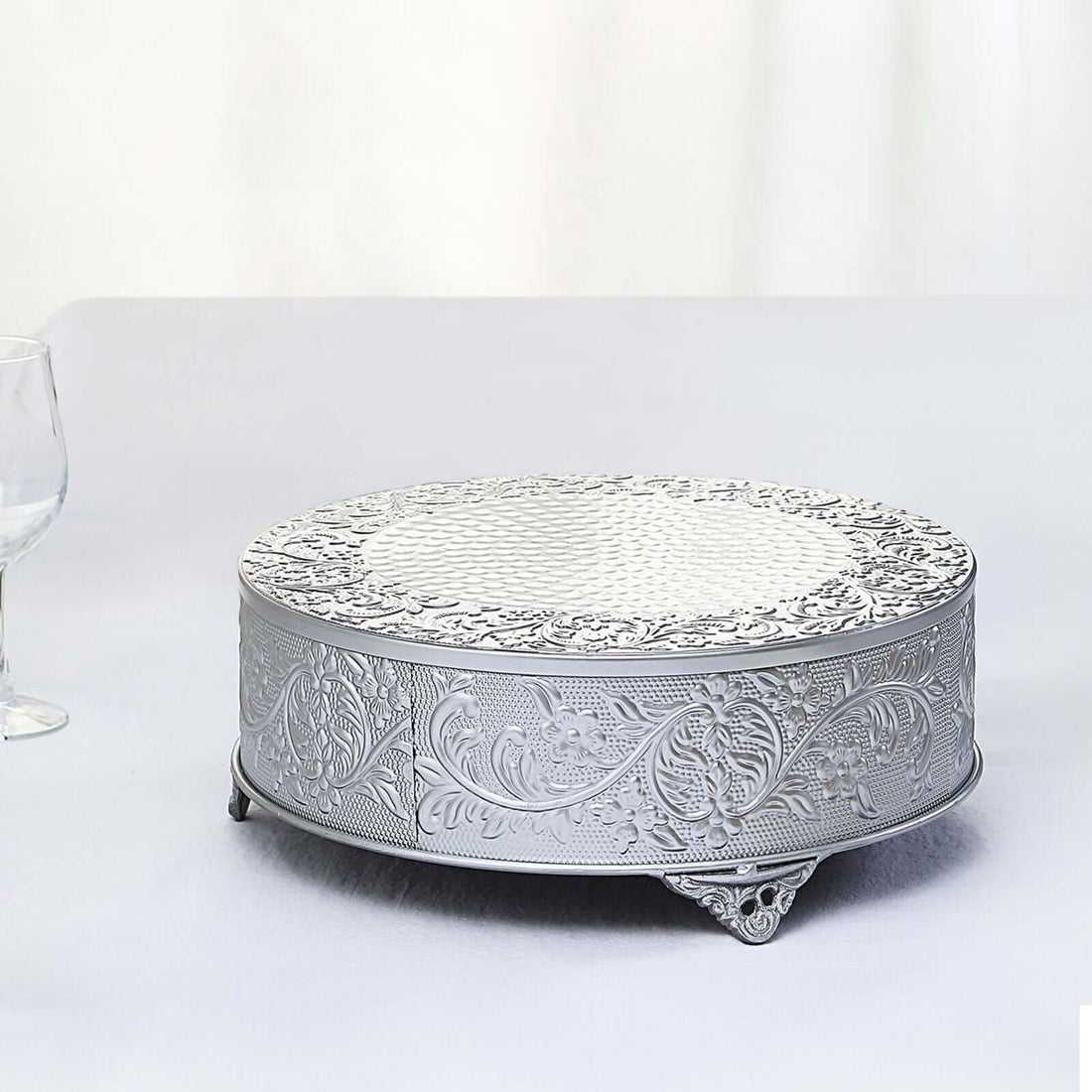 Silver decorative cake stand with intricate floral design.