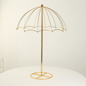 Gold decorative umbrella stand on a white table.