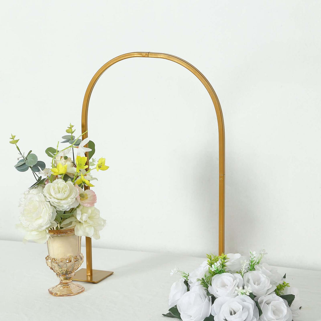 Gold floral arch with white and yellow flowers on a light background.
