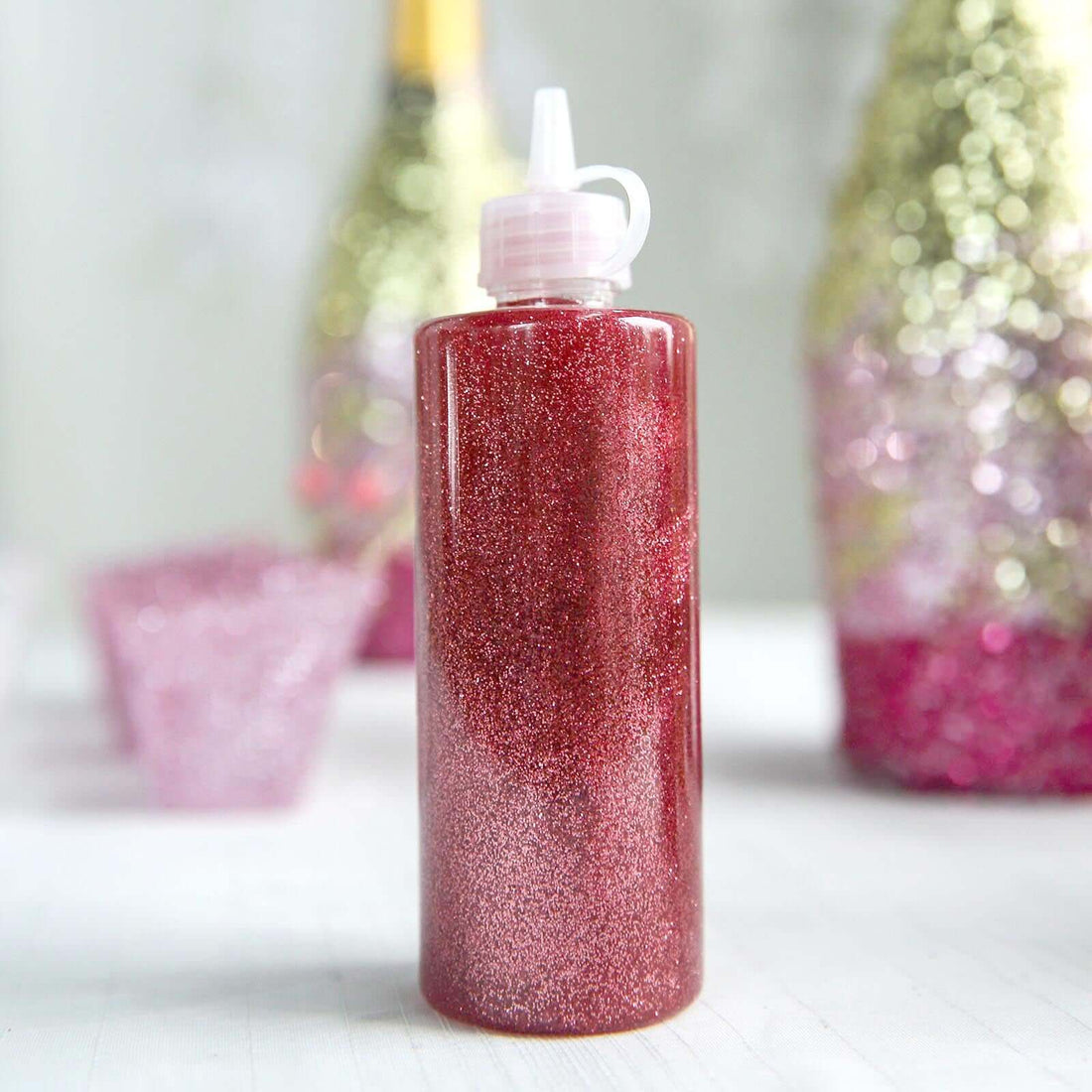 Red glitter glue bottle with a nozzle, ideal for crafting projects.