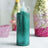 Teal glitter glue bottle on a plain background