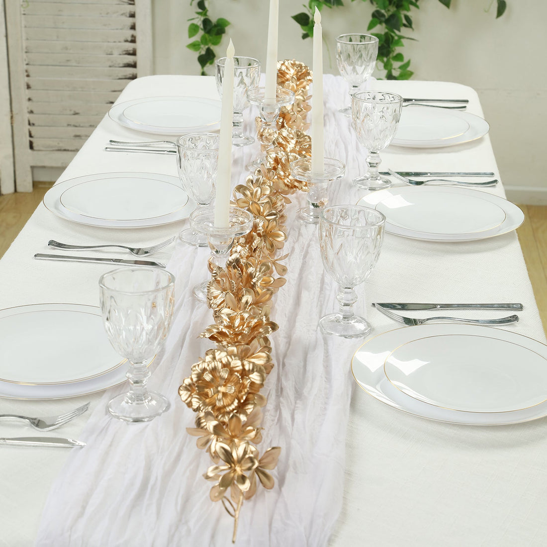 Elegant dining table set with gold floral centerpiece and crystal glassware.