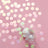 Iridescent confetti circles scattered with a glass on a pink background.