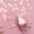 Rose gold confetti and glass on pink background.