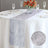 Elegant silver table runner on a white table with glassware and flowers.