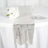 Silver table runner on a white table with flowers and glassware. 