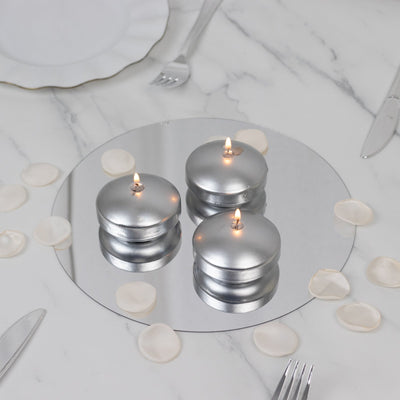 Silver candles on a mirrored tray with rose petals.