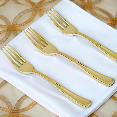 Set of three elegant gold forks on a white napkin.