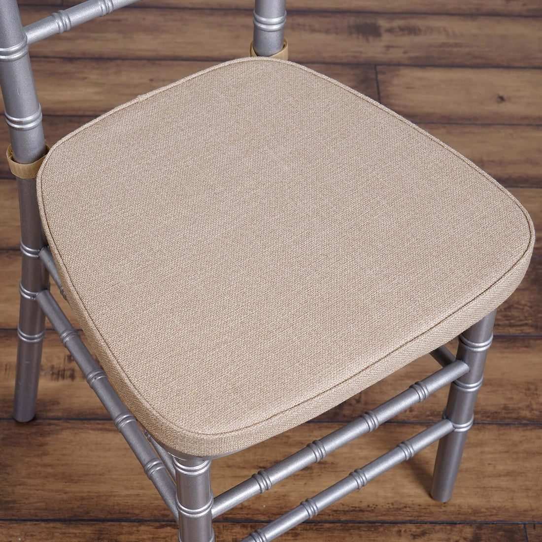 Silver chiavari chair with a beige cushioned seat.