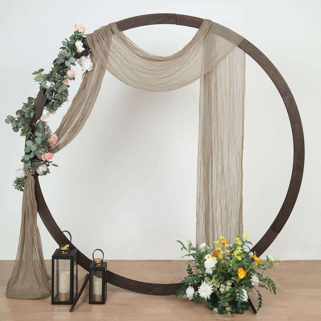 Decorative floral arch with draped fabric and lanterns for events or photography.