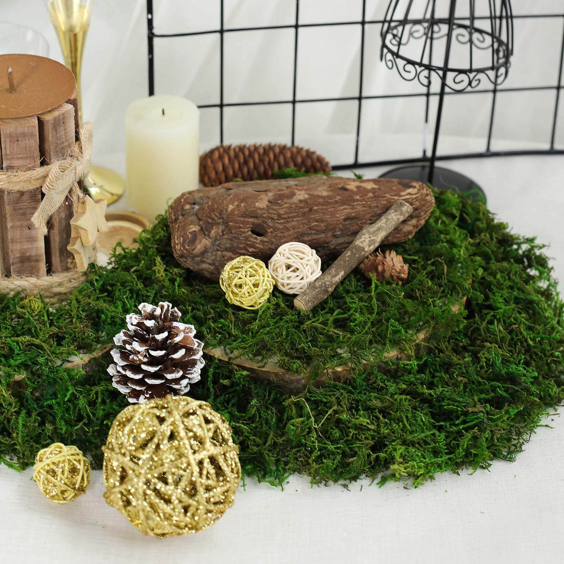 Decorative natural elements with moss, pinecones, and woven orbs on a table.
