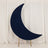 Navy crescent moon decor on a wooden stand against a white backdrop