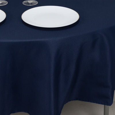 Navy blue tablecloth draped elegantly over a round table with plates and glasses.