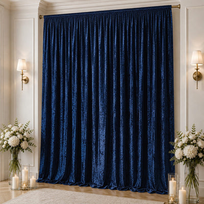 Navy blue velvet pleated curtains with elegant wall sconces and floral decor