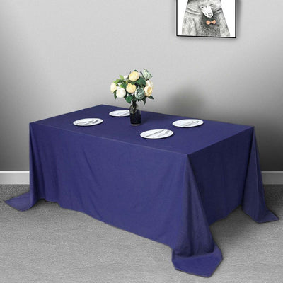Navy blue tablecloth draped over a dining table with plates and a vase of flowers.