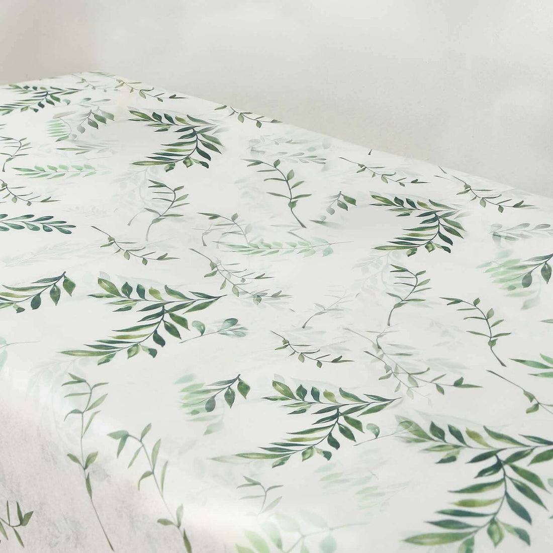 Floral-patterned tablecloth with green leaves on a light background.