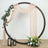 Decorative wedding arch with drapes, flowers, and lanterns on a neutral background.