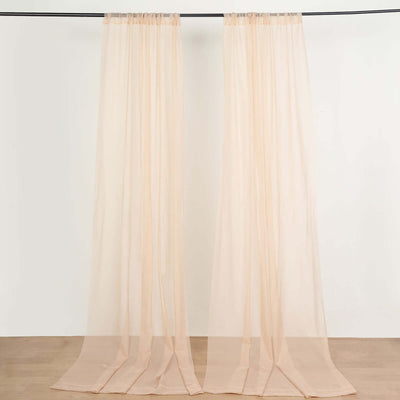 Sheer peach curtains hanging from a black rod against a plain background