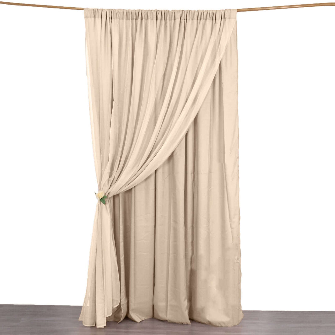 Beige curtain hanging on a rod, elegantly draped with a tieback.