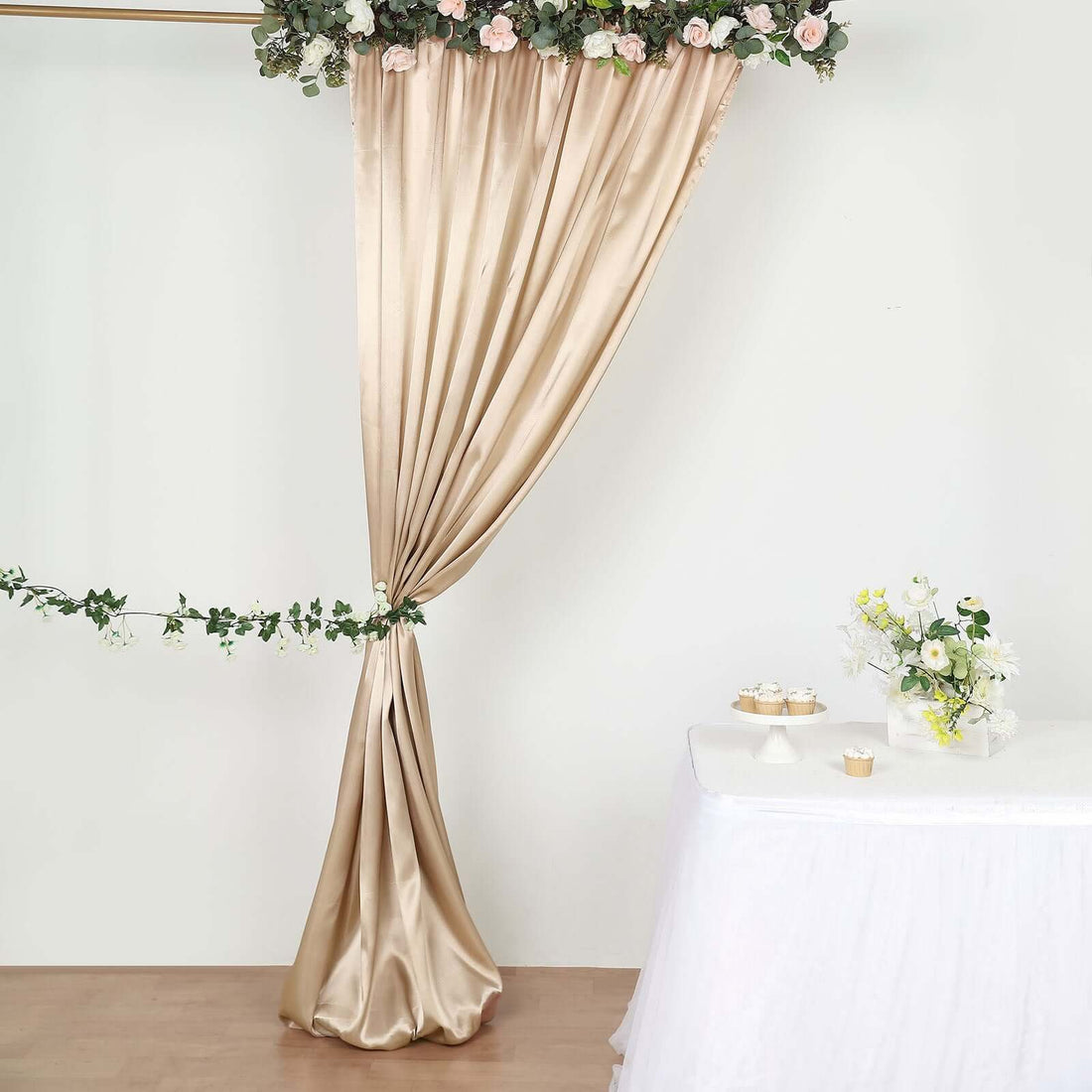 Elegant beige satin curtain with floral decor and table setting.