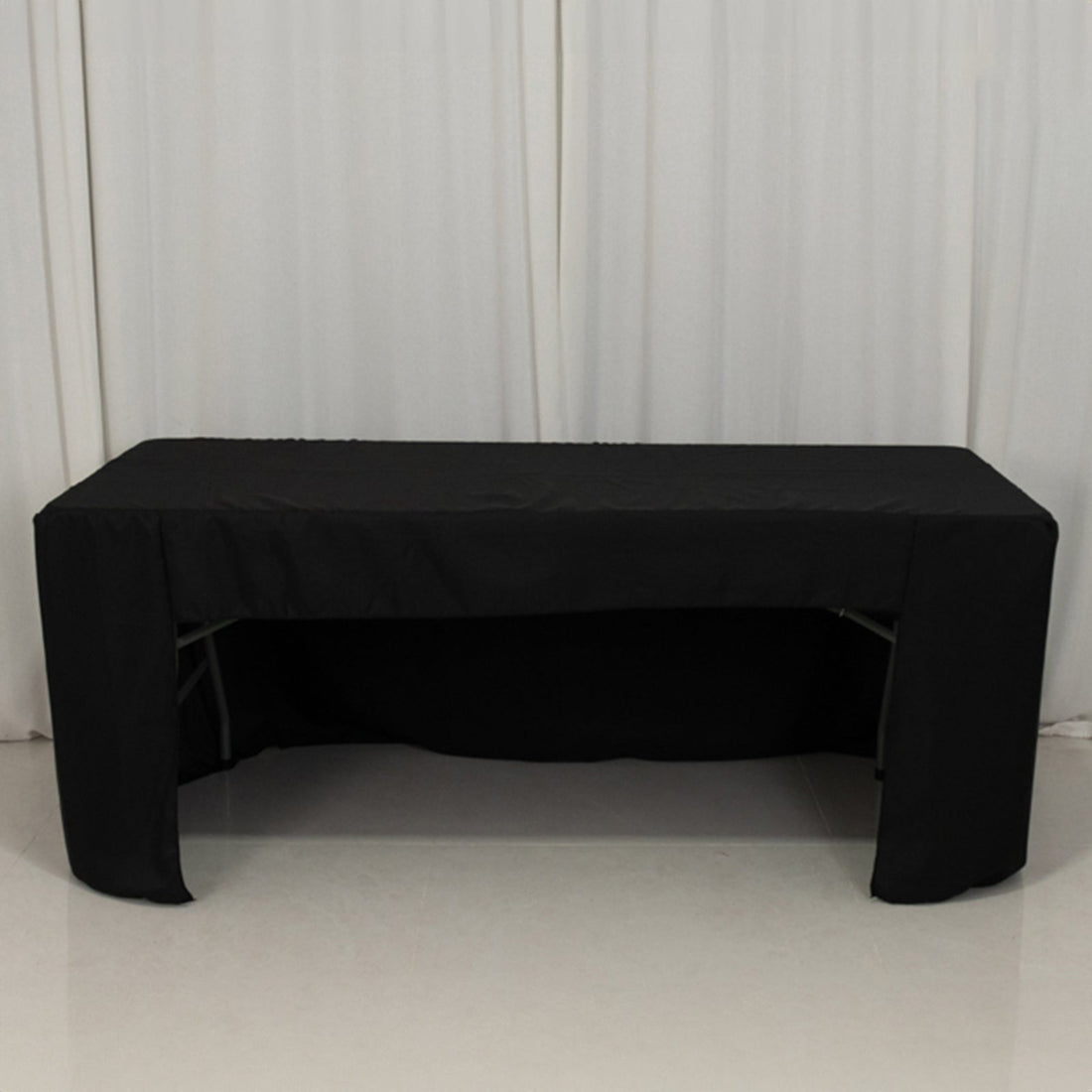 Black table cover on a table with a plain backdrop.